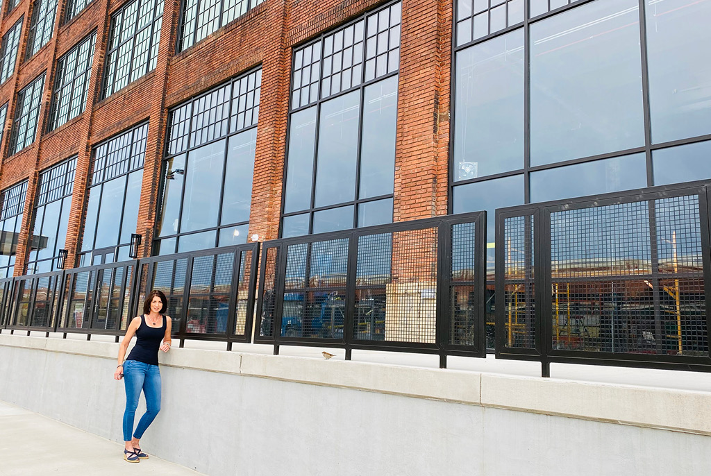 Kim Ford SIOR, LEED AP leaning on large office building